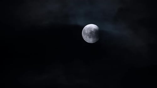 Teilweise verfinsterter Mond, der durch dunkle Wolken am Nachthimmel scheint