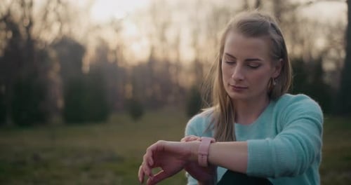 Woman Checking Time on Smartwatch in Park