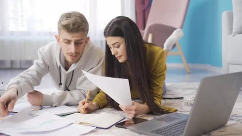 Jeune couple d'étudiants étudiant à la maison et discutant avec des amis sur un chat vidéo sur ordinateur portable.