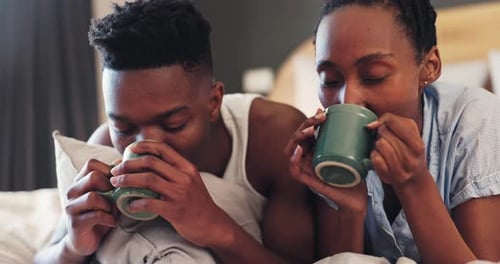 Couple Lying in Bed Together Drinking Coffee