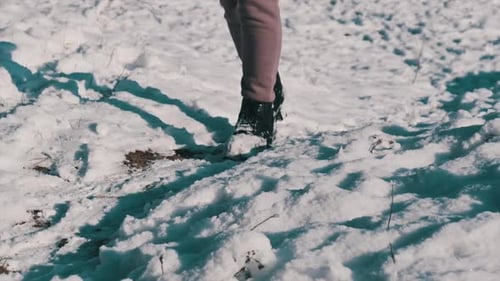 Female Legs with Winter Boots Walking By a Snow Covered Walkway in Winter Forest