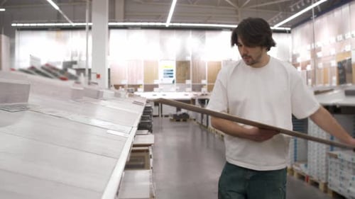Man Selects Laminate Plank in Flooring Aisle
