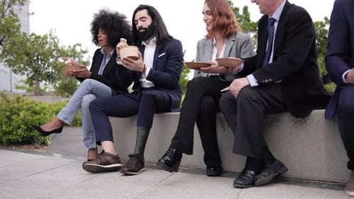 Empresarios comiendo comida para llevar durante la pausa del almuerzo reunidos fuera de la oficina