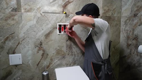 Plumber Installing Toilet Tank in Restroom