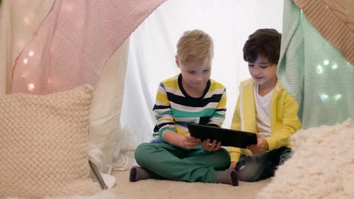 Two Boys Playing Together With Tablet in Homemade Tent