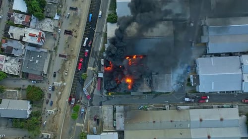 Vue aérienne par drone d'une usine en feu, montrant toute l'étendue de l'incendie et de l'étendue du barrage