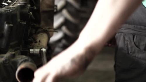 Mechanic Working on Tractor Engine with Socket Wrench