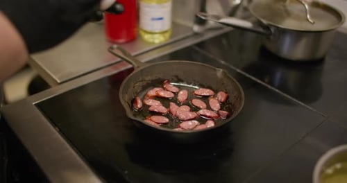 Chef Cooking Sausage and Eggs in Frying Pan