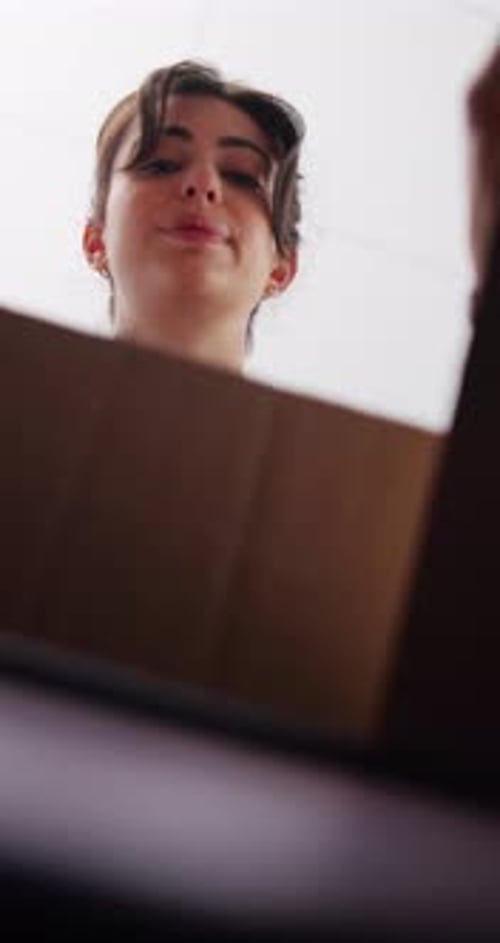 Smiling Woman Opens Box From Below Angle