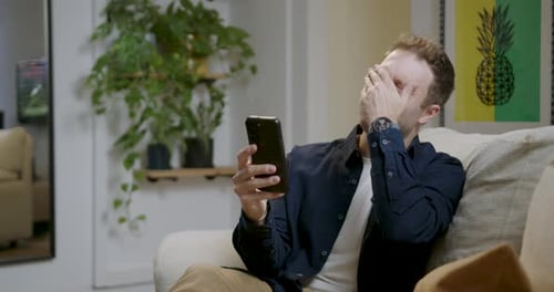 Man Laughing and Smiling While Looking at Phone