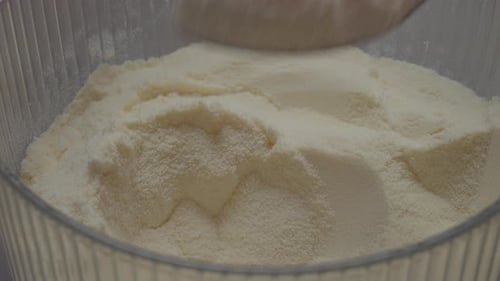 Spoonful of smooth powdered milk in a clear container