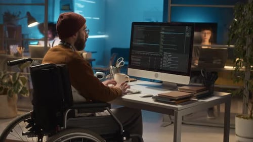 Man in Wheelchair Working on Computer Late at Night