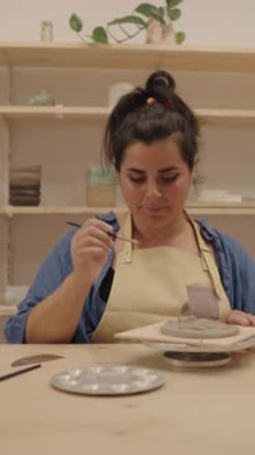 Ceramist Painting a Clay Sculpture in Workshop
