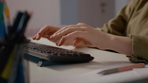 Woman typing on keyboard while working from home in a cozy office setting