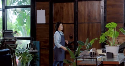 Asian senior female cafe owner smiling greeting customer at entrance hospitality communication