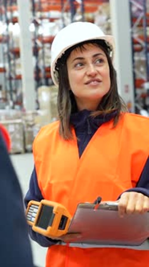 Warehouse Worker Smiles Holding Scanner and Clipboard
