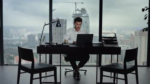 Excited businessman celebrates success reading good news on laptop in modern office