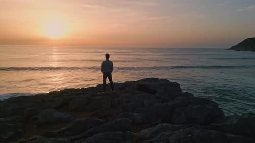 Dark Silhouette Enjoying Sunrise Ocean Horizon at Volcanic Cliffs Back View. Unrecognizable