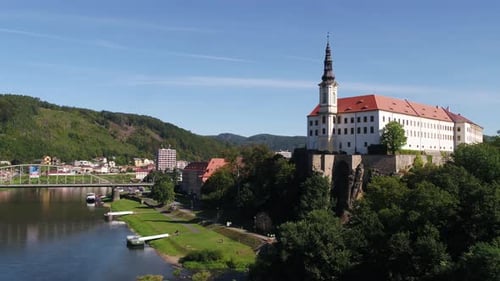 Vista ampliada del castillo y la ciudad de Decin rodeados de bosque al amanecer