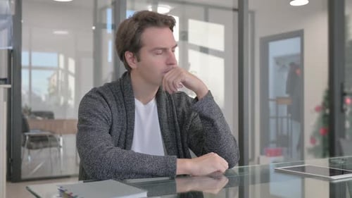 Pensive Young Man Sitting in Office
