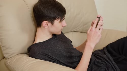 Teen relaxing on couch using smartphone