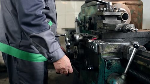 Man in uniform is operating cutting machine in the factory