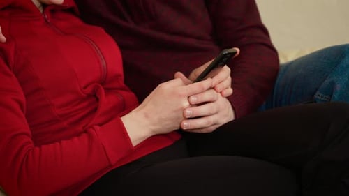 Couple Holding a Phone Inside Relaxing on a Couch