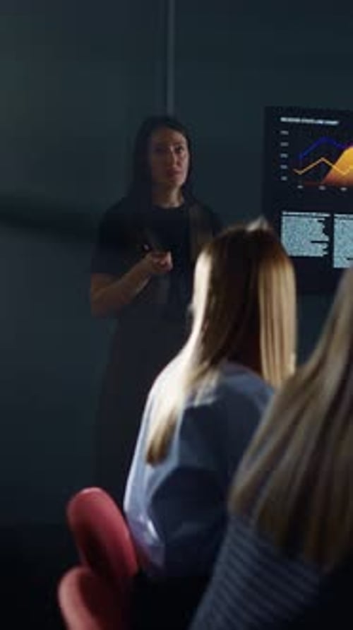 Businesswoman Giving Presentation to Colleagues in Dark Room