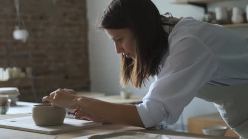 woman decorating a cup in a pottery workshop