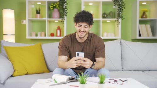 Smiling Young Adult Using Smartphone on Cozy Couch