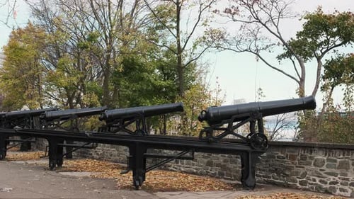 Row of weathered iron cannons stand atop the stone ramparts of Quebec City