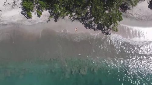Drone view of a girl lying on a paradise beach in Costa Rica