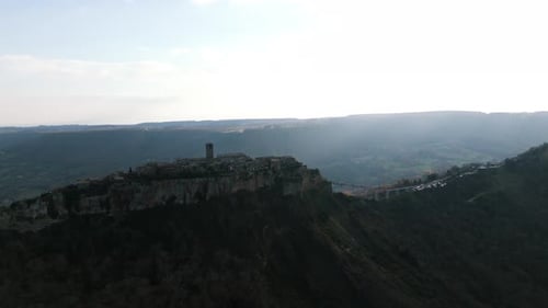 Distant shot of Civita di Bagnoregio at sunrise, Italy. Aerial backward