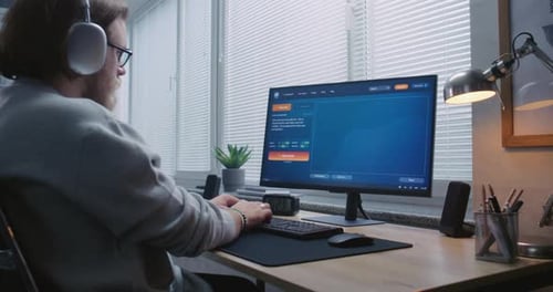 Adult Man in Headphones Types Prompt in AI Video Generator on PC