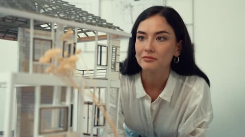 Skilled architect turns house model around to inspect construction. Immaculate.