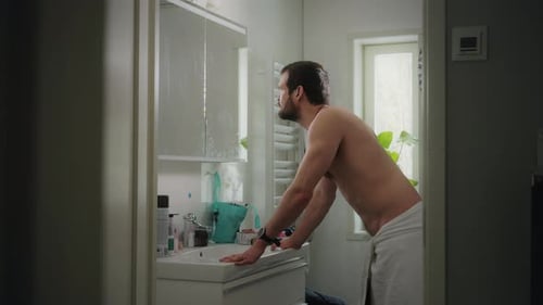 Man Wrapped in Towel Looking in Mirror