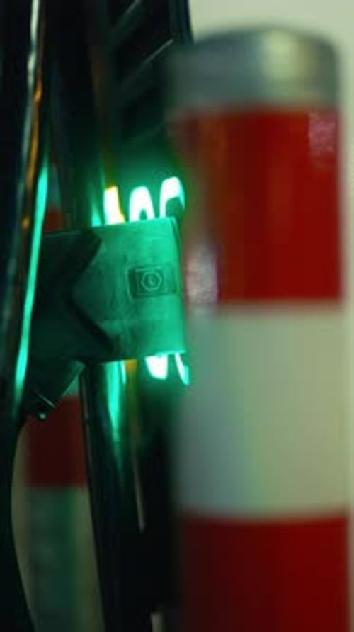 Detailed View of a Green Light Reflecting on a Metallic Structure with a Safety Bollard