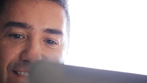 Man Looking at Tablet Device, Smiling