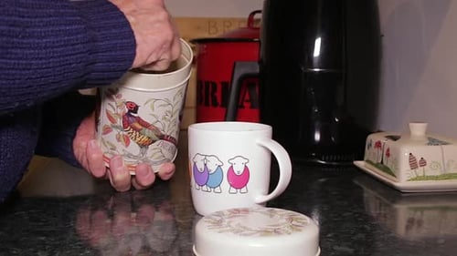 Hands Stirring Sugar into Mug and Pouring Milk
