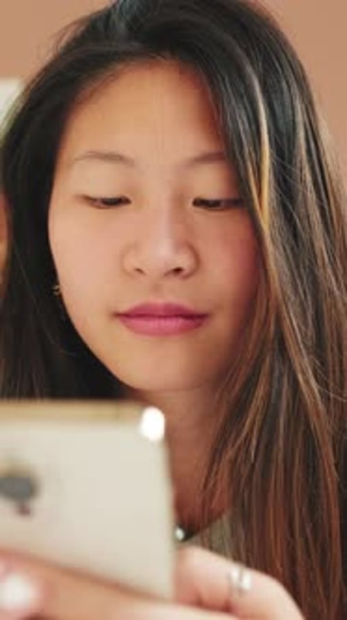 Close-up, young woman sitting on the sofa writes SMS with a mobile phone