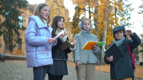 Group of Dissatisfied Teen Classmates Gesturing Thumbs Down Looking at Camera Standing Outdoors