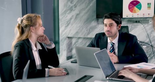 Weißer erwachsener männlicher Manager erklärt einer jungen weißen Mitarbeiterin im Besprechungsraum die Präsentation