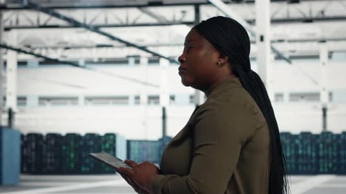 Data Center Technician Runs Equipment Checkups with Digital Device in Data Center