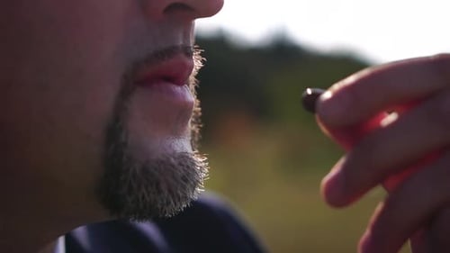 Adult Man Taking a Small Dark Pill Outdoors