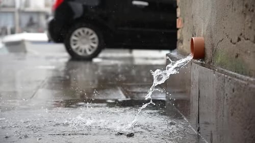 Water Draining From Pipe in City Street