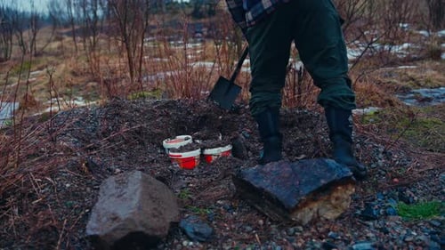 A Person is Covering Containers Filled With Soil and Seeds in a Pit - Close Up