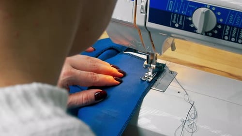 Closeup in a Sewing Workshop on a Machine the Seamstress Master Makes Cut on a Blue Fabric