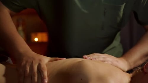 Männerhände massieren den nackten Rücken des Mädchens Ein professioneller Massagetherapeut in einem grünen Hemd gibt eine