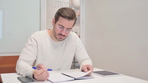 Reading Young Man Checking Documents in Office