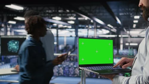 Close Up of Data Center Employee Doing Maintenance Tasks on Green Screen Laptop